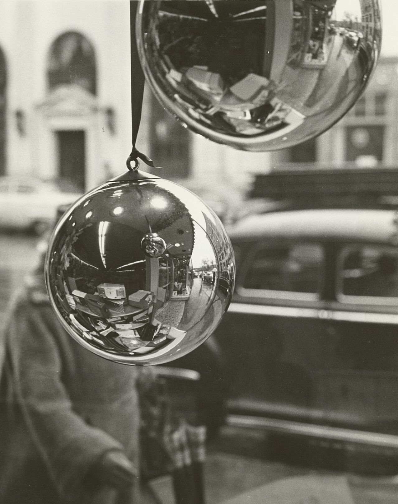 A Christmas window display is reflected in a Christmas bulb, Dec. 1957.